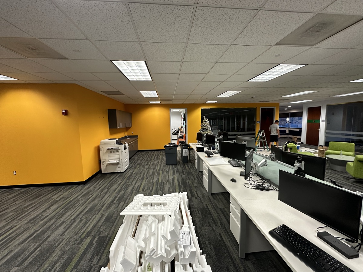 Open plan office with yellow walls and workstations by J&B Painting