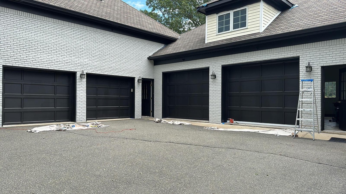 White painted brick home with black garage doors